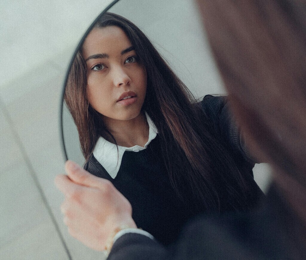 Brunette woman looking at reflection in mirror
