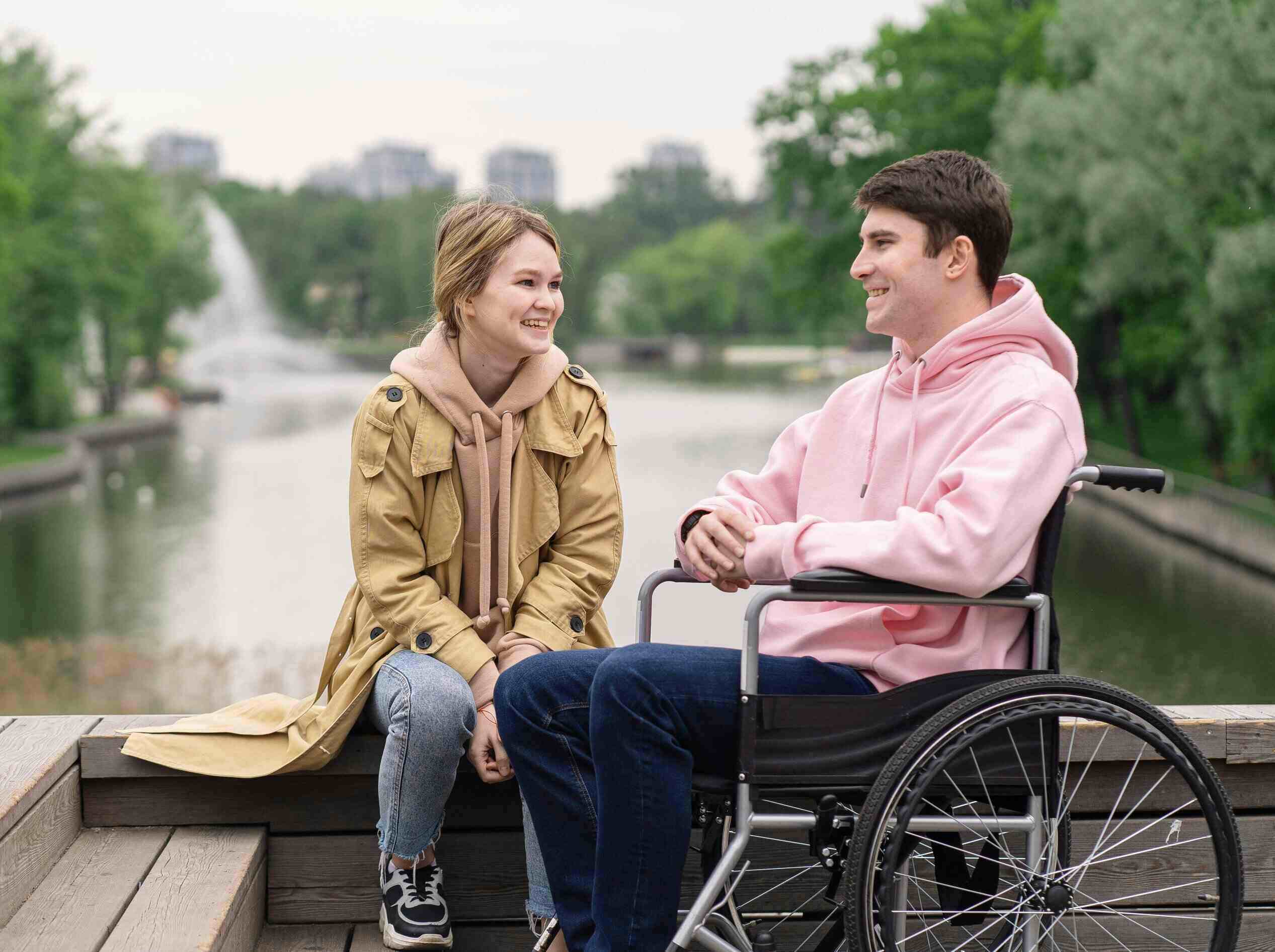 Happy couple talking while seated by a pond in a city park